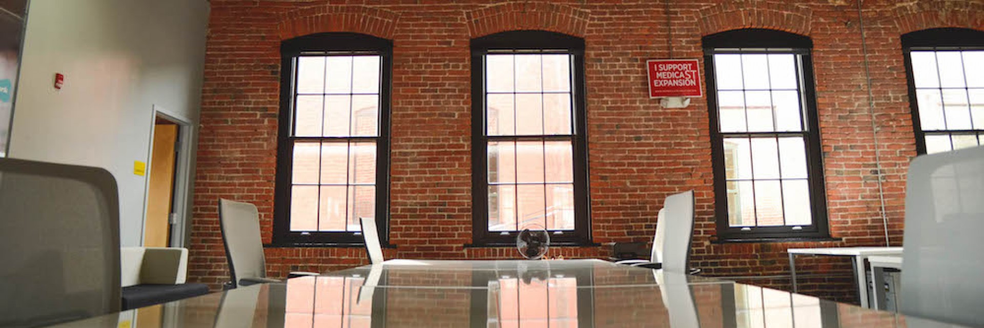 An exposed brick office as is typically occupied by startups in San Francisco and Brooklyn. This image depicts an empty conference room with a table and chairs prior to a meeting