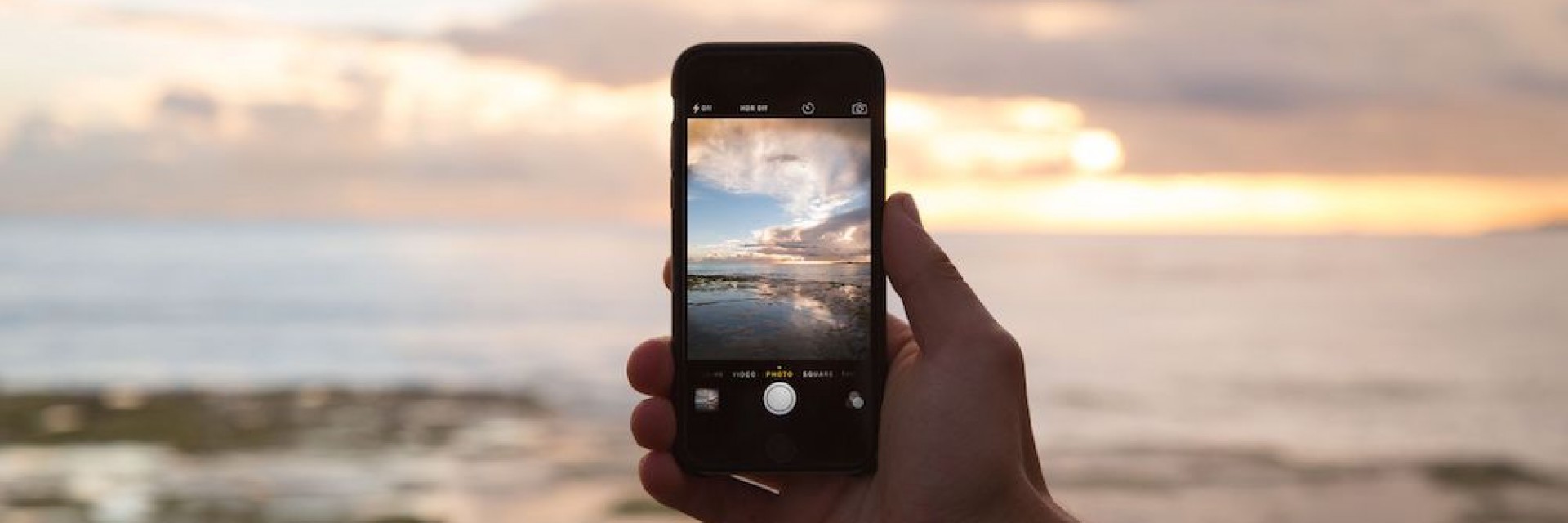 A man photographing a beautiful sunset on his smart phone