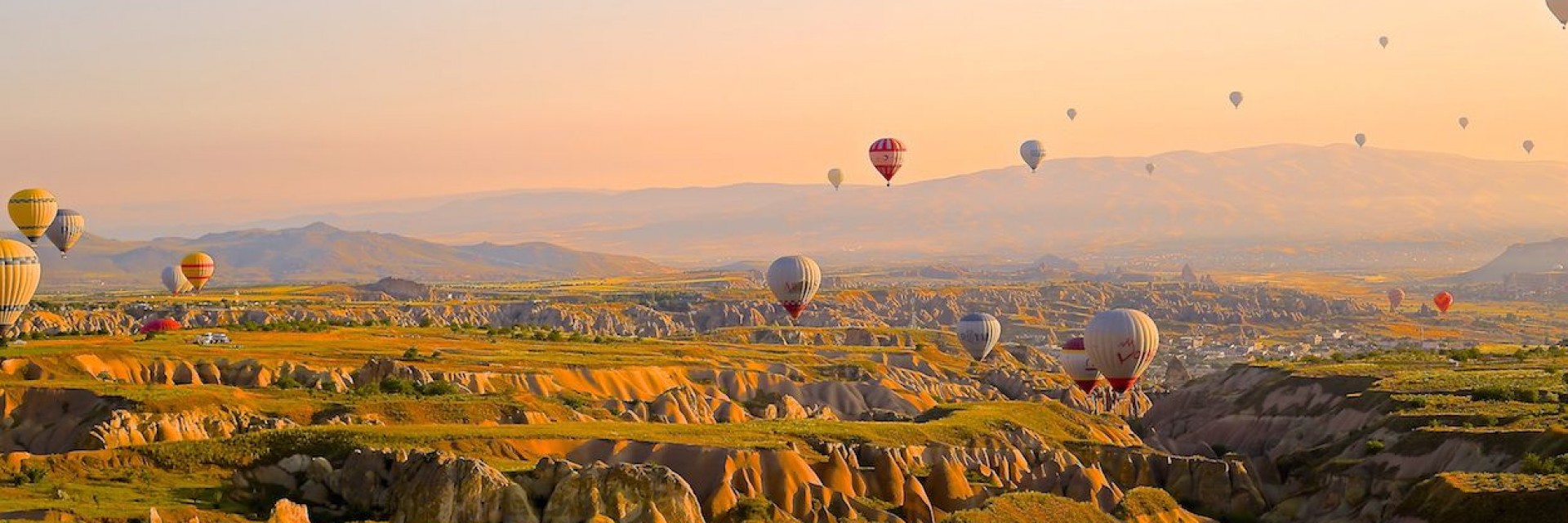Hundreds of hot air balloons floating over the grand canyon amid a lovely sunset